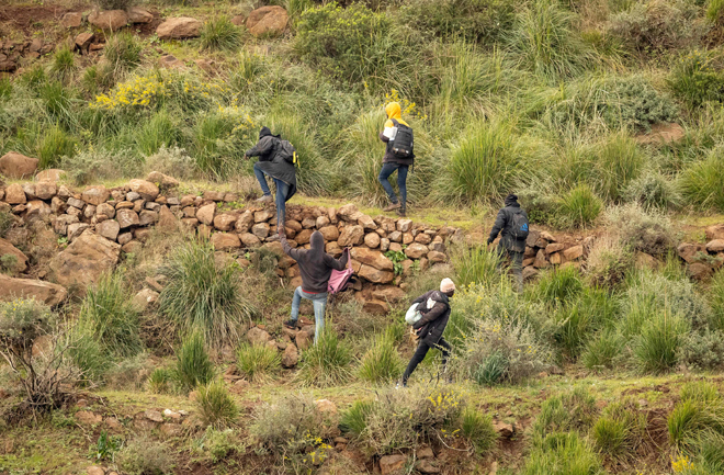 Migrants climb a ledge along a mountain path after an attempted assault on the border fence separating Morocco from Spain's North African Melilla, near Nador, on Friday (AFP photo)