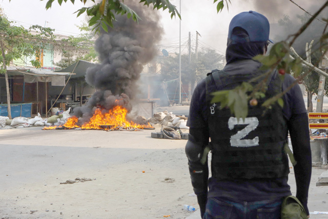 This photo taken and received courtesy of an anonymous source on Monday shows a protester looking at a burning barricade during a crackdown by security forces on demonstrations against the military coup in Mandalay (AFP photo)