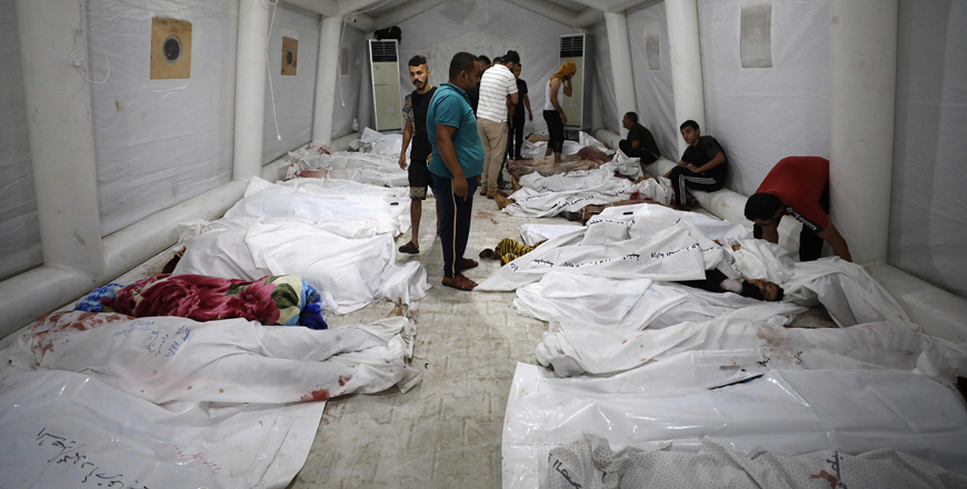 People stand over bodies of Palestinians killed in Israeli air strikes on the Ahli Arab hospital in central Gaza after they were transported to Al Shifa hopsital, on Tuesday (AFP photo by Dawood Nemer)