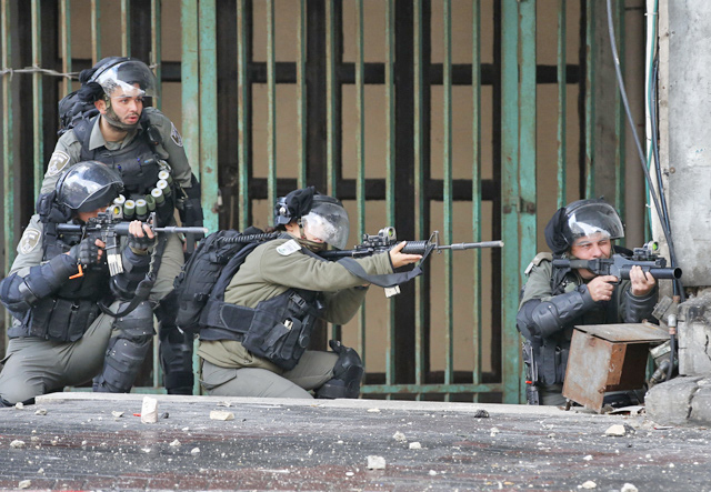 Israeli soldiers take aim during confrontations with Palestinian protesters in the southern West Bank city of Hebron, on December 9, amid a general strike over Israeli settlement activity  (AFP photo)