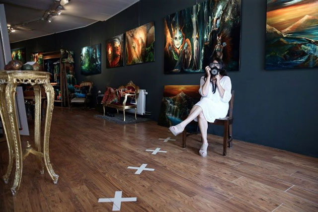 Artist Sylvia Reijbroek, who owns an art gallery, wears a face mask on the Belgian side of her shop, marked out by white crosses, because Belgium makes face coverings compulsory to fight the coronavirus (AFP photo)