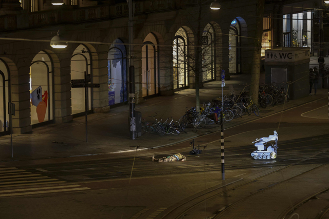 A man in camouflage clothing lies next to a police robot in a street after the hostage-taking ended in Amsterdam, on Tuesday (AFP photo)