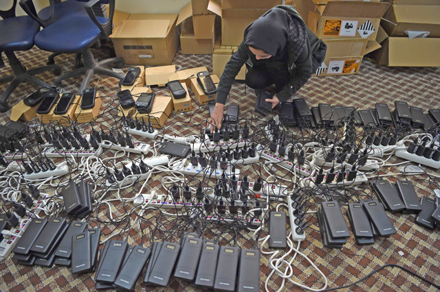 In this photo taken on Wednesday, an Afghan employee of the Independent Election Commission charges power bank devices. Voters will wrestle with a newspaper-sized ballot on October 20, racing to find their candidate as quickly as possible under the threat of a militant attack (AFP photo)