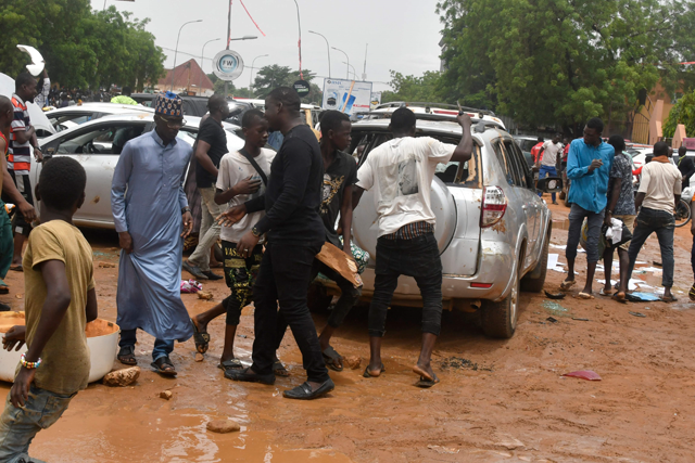 Supporters of the Nigerien defence and security forces are seen next to a vehicle with smashed windows at the headquarters of the Nigerien Party for Democracy and Socialism, the party of overthrown President Mohamed Bazoum, in Niamey on Thursday (AFP photo)
