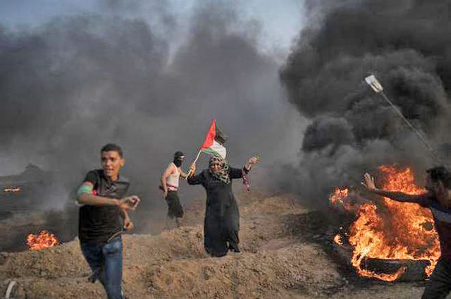 Palestinian protesters run for cover as other hurls stones during a protest at Gaza Strip's border with Israel, east of Gaza City, on Friday (AP photo)
