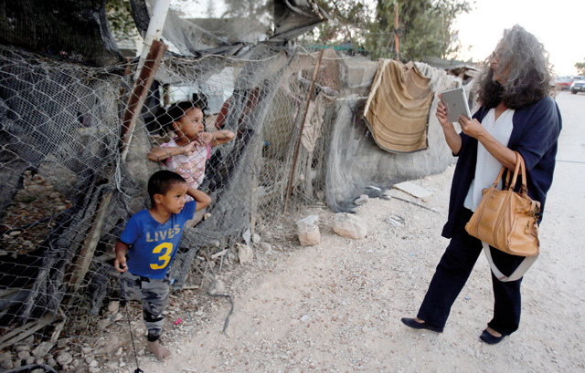 A member of a delegation of the European Parliament takes photos of Palestinian children during a visit to the Bedouin village of Khan Al Ahmar, in the occupied West Bank, on Wednesday (Reuters photo)
