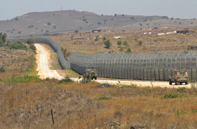 Israeli army vehicles patrol the border fence with Syria in the Golan Heights on July 4 (AFP photo)