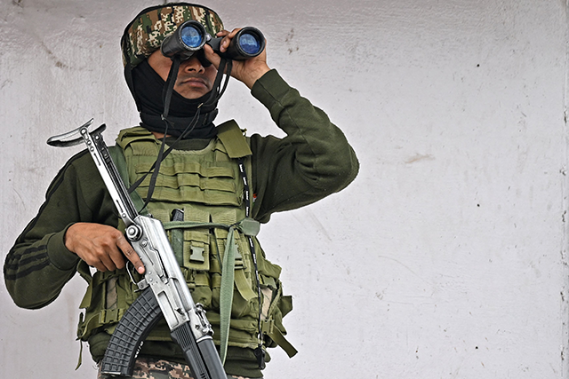 An Indian paramilitary personnel conducts surveillance using binoculars as he stands atop a commercial building in Srinagar on May 5, 2025 (AFP photo)