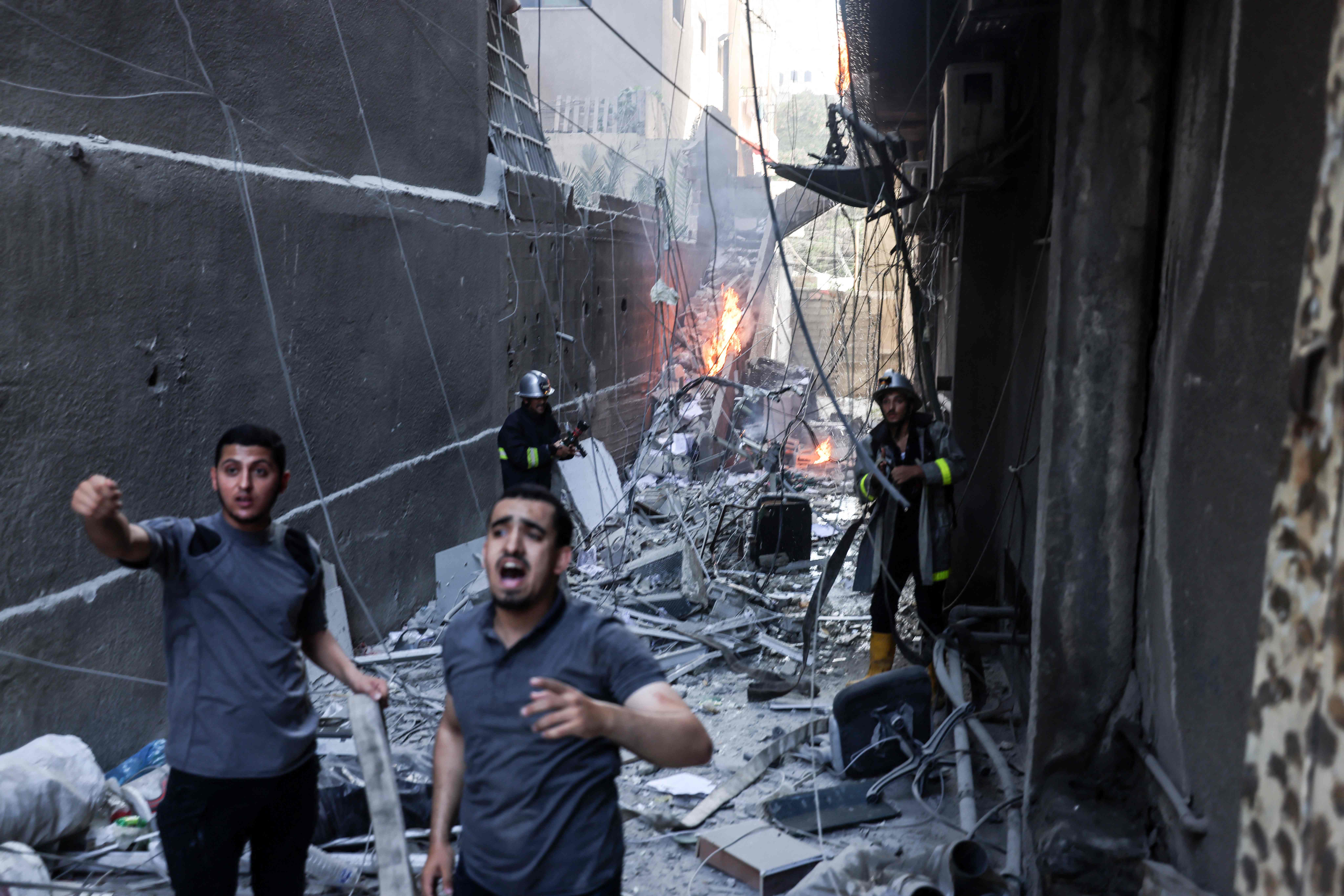 Rescuers and firefighters put out a fire amid the destruction following an Israeli air strike on Gaza City, on Friday (AFP photo)