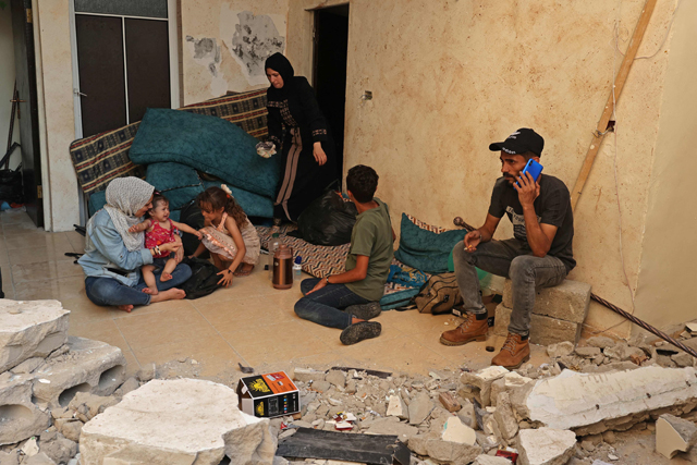 Wissam Joudeh (right) sits with his family in his partially destroyed house in Rafah in the southern Gaza Strip on Tuesday (AFP photo)