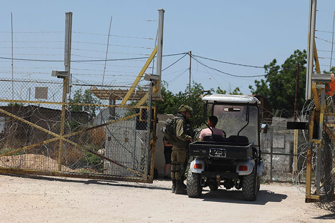 A member of Israeli forces stops a vehicle at a crossing, near the site where a Palestinian worker was shot dead, in the West Bank city of Qalqilya, on Sunday (AFP photo)