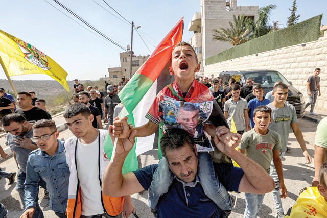 Ahmed, son of Mujahed Dawood, a Palestinian who died after being critically wounded the previous day during confrontations with Israeli forces in the village of Qarawat Bani Hassan, chants slogans as he is carried on the shoulders of a man marching during the funeral in the village of Haris in the occupied West Bank on Sunday (AFP photo)