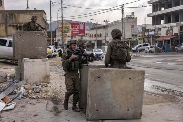 Israeli soldiers stand guard by concrete blocks in the Palestinian village of Huwara, south of Nablus in the occupied West Bank, on Wednesday (AFP photo)