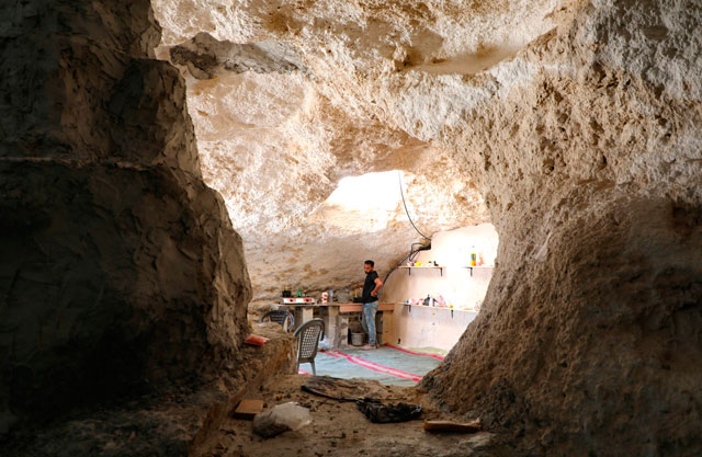 Ahmed Amarneh stands by a tap at the kitchen of his home which he built in cave, in the  village of Farasin, west of Jenin, in the northern occupied West Bank, on August 4  (AFP photo)