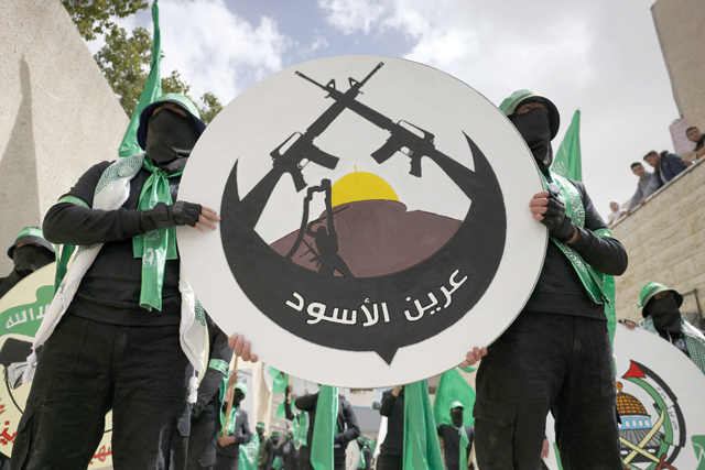 Student supporters of the Islamist Movement Hamas carry a logo of the Lion's Den armed group (Areen Al Asood), during a university election campaign rally in the West Bank city of Hebron on Monday (AFP photo)