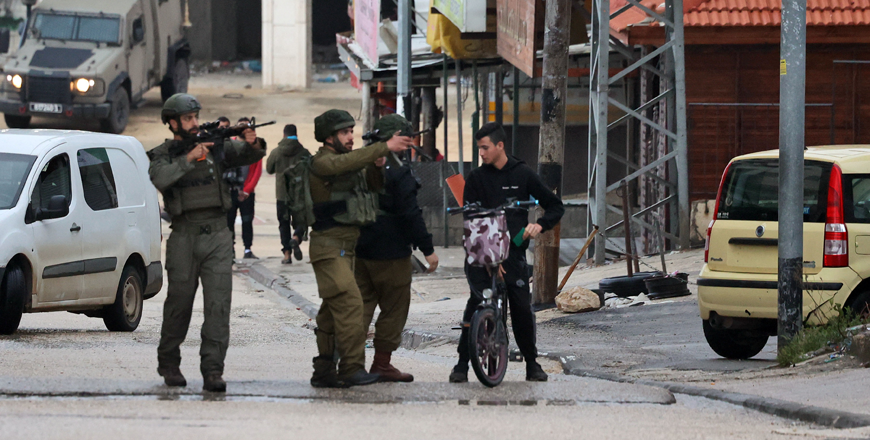 Israeli soldiers check the ID card of a Palestinian youth as they patrol the town of Huwara, in the occupied West Bank, following a reported shooting attack on an Israeli settler's car, on Sunday (AFP photo)
