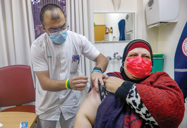 A Palestinian woman receives the Pfizer-BioNTech COVID-19 vaccine at the Clalit Health Services in the Israeli-occupied East Jerusalem, on Saturday (AFP photo)
