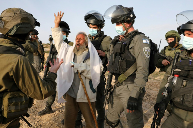 An elderly Palestinian man scuffles with Israeli security forces as he protests the removal by an army bulldozer of a temporary health unit in the village of Al Mufagara, near Yatta, south of the West Bank city of Hebron, in January (AFP photo)