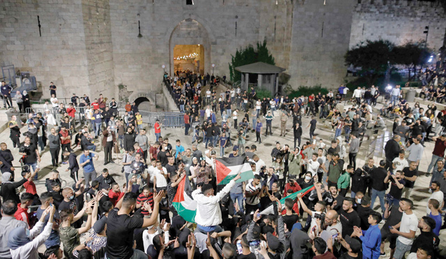 Palestinian protesters raise national flags as they gather near the Damascus Gate in Jerusalem's Old City on Sunday (AFP photo)