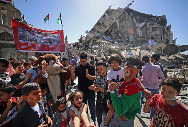 Palestinians wearing cartoon-inspired costumes entertain children on the rubble of Al Shourouk tower, recently destroyed by Israeli strikes, in Gaza City, on Tuesday  (AFP photo)