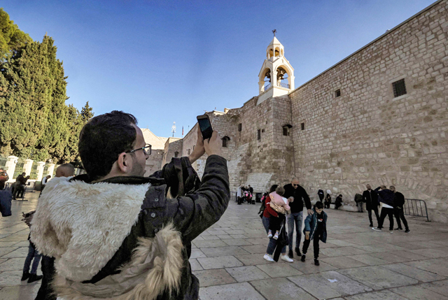 Milad Ayyad, a Palestinian Greek Orthodox Christian from Gaza, tries to photograph the Church of the Nativity, the traditional place of Christ’s birth, as he stands in the Manger Square in the biblical city of Bethlehem in the occupied West Bank on Sunday  (AFP photo)