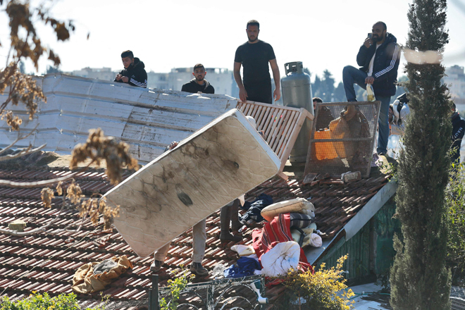 Palestinian men barricade themselves on the roof of a house as Israeli forces prepare to evict a family from the same building on Monday in Jerusalem’s East district of Sheikh Jarrah  (AFP photo)