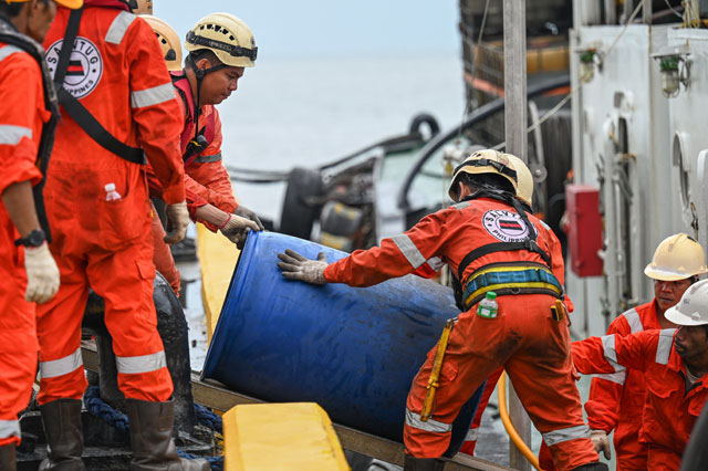 Crew of a private company loads a barrel of oil spill dispersant to be used in the oil spill response, at a port in Limay, Bataan on Friday (AFP photo)