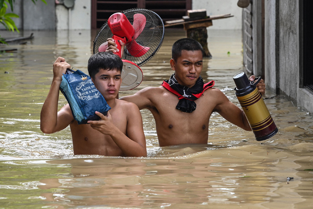 Residents carry their belongings while evacuating from their submerged homes in the aftermath of Super Typhoon Noru in San Ildefonso, Bulacan province, on Monday (AFP photo by Ted Aljibe)