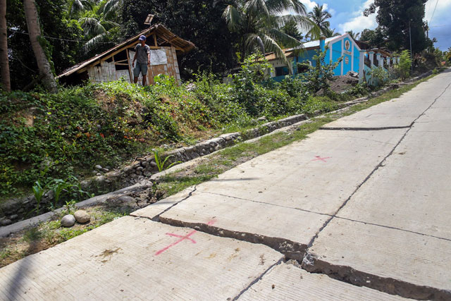 A resident stands near a huge crack in a cemented road caused by a 6.4 magnitude earthquake the night before, in the town of Magsaysay in Davao del Sur on the southern Philippine island of Mindanao on Thursday (AFP photo)