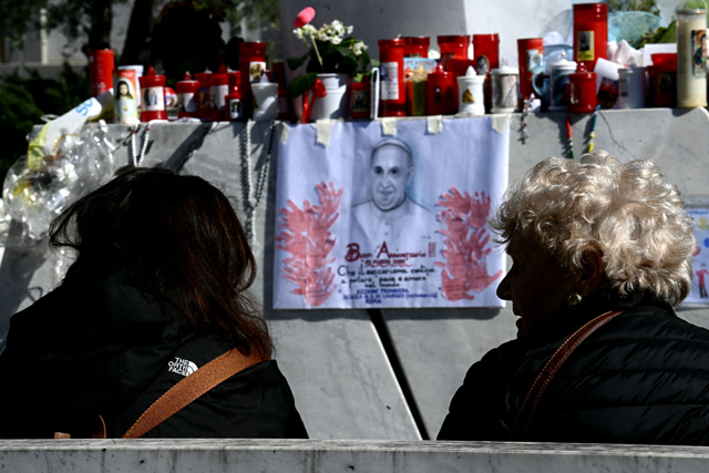A woman prays under the statue of pope John Paul II at the Gemelli Hospital where Pope Francis was hospitalised in Rome on Tuesday (AFP photo)