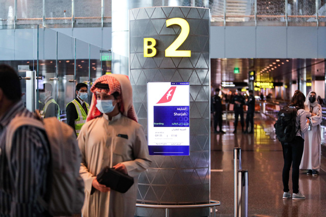 Mask-clad travellers wait at the gate before boarding the first flight to Sharjah after the resumption of air travel between Qatar and the United Arab Emirates, at Qatar's Hamad International Airport, on Monday (AFP photo)