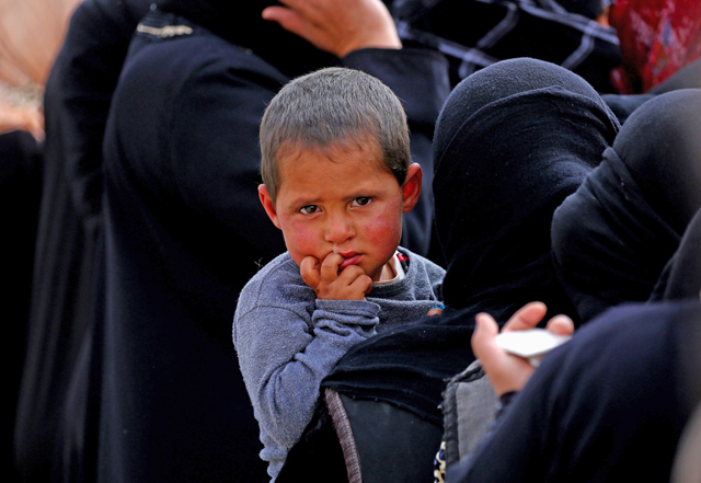 A boy looks on as displaced Syrians from Tabaqa and Raqqa, who fled the fighting between the US-backed Syrian Democratic Forces and Daesh group militants, wait for receiving aid parcels near the northern Syrian village of Jarniyah, on Thursday (AFP photo)