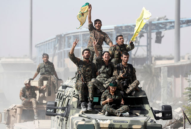 Syrian Democratic Forces fighters ride atop military vehicles as they celebrate victory in Raqqa, Syria, on Tuesday (Reuters photo)