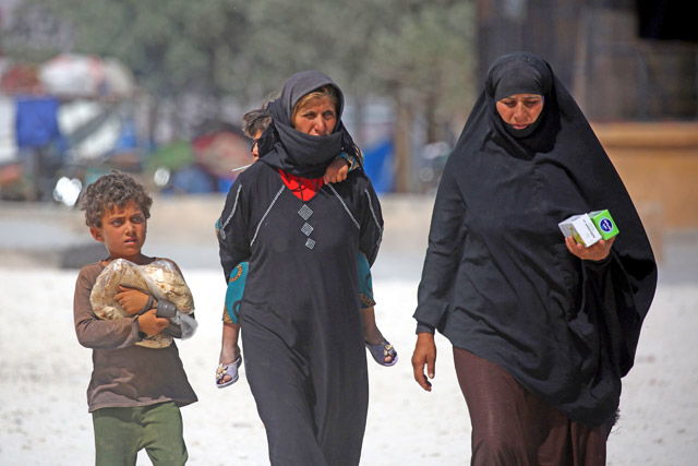 Displaced Syrians walk at a temporary camp in the northern Syrian village of Ain Issa on Sunday, where many people who fled the Daesh group stronghold of Raqqa are taking shelter (AFP photo)
