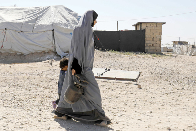 A woman walks with a child at a camp for Daesh group-affiliated people in the northern Syrian village of Malikiya near the border with Turkey on September 29 (AFP photo)