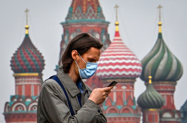 A man wearing a face mask to protect against the coronavirus disease uses his mobile phone as he stands in front of St Basil's Cathedral in central Moscow on Wednesday (AFP photo)