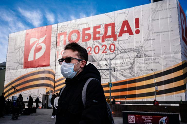 A man wearing a face mask against the spread of the coronavirus walks past a banner for the now much reduced 75th anniversary celebrations in Moscow marking the victory over Nazi Germany in World War II (AFP photo)