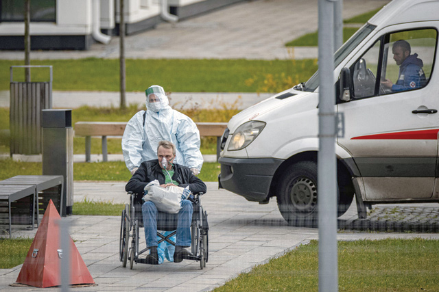 A medical staff member pushes a person on a wheelchair at the COVID-19 infected patients section at the Kommunarka Hospital outside Moscow on Friday (AFP photo)