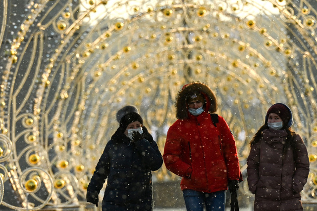People wearing protective facemask walk past festive decorations set for Christmas and the upcoming New Year’s celebrations, in Moscow on Sunday (AFP photo)