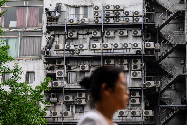 A woman walks past air-conditioning units outside a building in Seoul on April 30 (AFP photo)