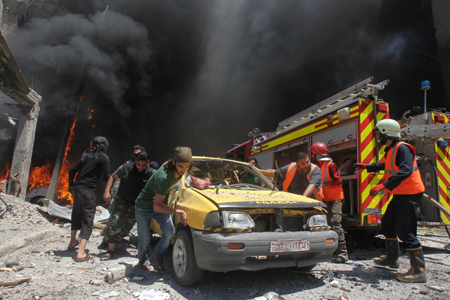 Civil defence members and rescuers push a car at a site hit by air strikes in Idlib city, Syria,  on Sunday (Reuters photo)