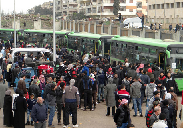 Opposition fighters and their families gather as they prepare to board a bus, ahead of their evacuation from the rebel-held Waer neighbourhood in the central city of Homs on Saturday, during the first phase of the Russian-supervised deal to complete the evacuation of fighters and civilians (AFP photo)