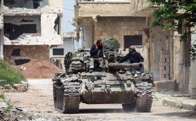 Syrians ride on the turret of a moving tank in the rebel-held area of Daraa, in southern Syria, on Wednesday (AFP photo)