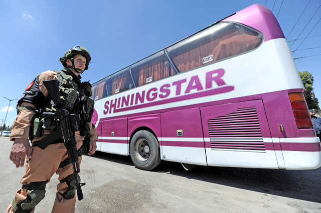 A Russian soldier stands guard near a bus as rebel fighters and their families evacuate the besieged Waer district in the central Syrian city of Homs, after an agreement reached between rebels and Syria’s army, Syria, on Sunday (Reuters photo)
