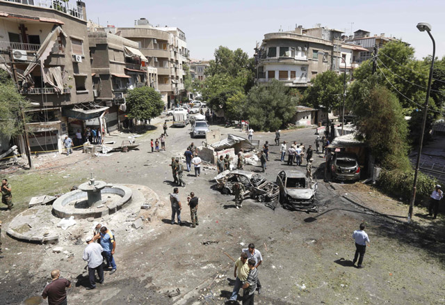 Syrians gather to inspect the damage at the site of a suicide bomb attack in the capital Damascus’ eastern Tahrir Square district on Sunday (AFP photo)