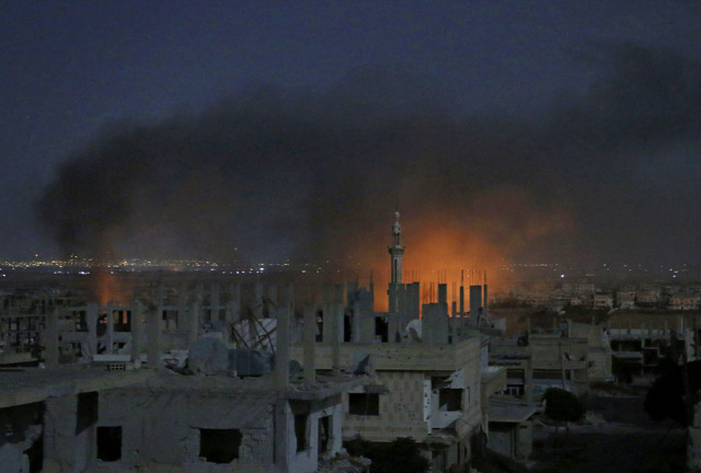 Smoke and flames rise from buildings following a reported government strike on a rebel-held area in Syria’s southern city of Daraa late on Monday (AFP photo)
