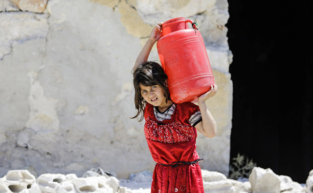 A Syrian girl carries a large jug of water on her back while on her way home, in the Kallaseh district of the northern city of Aleppo, on Wednesday (AFP photo)