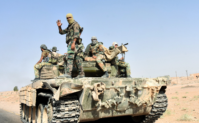 Members of the Syrian government forces ride on a tank, in the village of Kobajjep on the southwestern outskirts of Deir Ezzor province, on Wednesday, during the ongoing battle against Daesh militants (AFP photo)