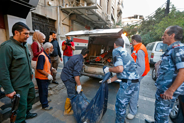 Syrian security forces carry the remains of a reported suicide bomber following an attack near the main police headquarters in Syria’s capital Damascus on Wednesday (AFP photo)