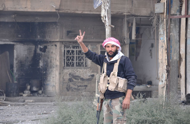 A Syrian pro-government forces member flashes the sign for victory as he patrols in the eastern city of Deir Ezzor on Saturday (AFP photo)